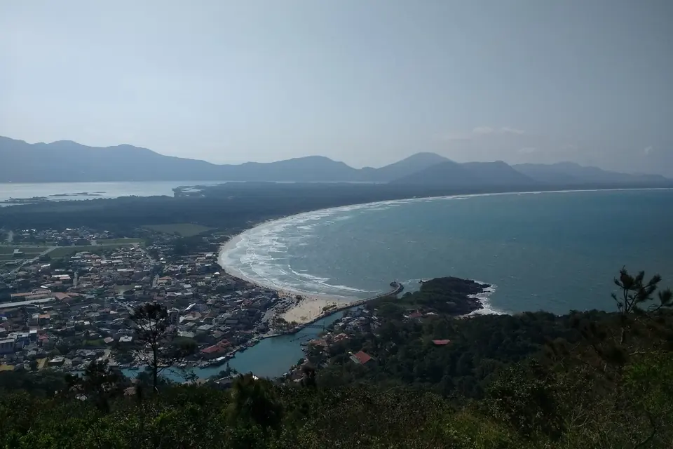 Vista elevada de Barra da Lagoa, en Florianópolis, con la playa en forma de media luna, el mar y los cerros verdes de fondo