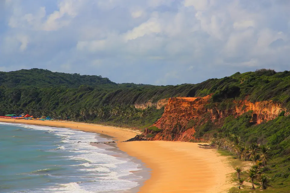 La Bahía de los Delfines en Pipa, con acantilados de arena roja, selva verde y una playa dorada junto al mar