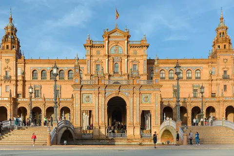Vista frontal del palacio de la Plaza de España de Sevilla, con sus torres y arcos de ladrillo y cerámica bajo un cielo despejado