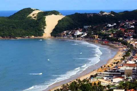 La bahía de Ponta Negra, en Natal, con el Morro do Careca y su duna de arena al fondo, el mar azul y la costa con edificios bajos